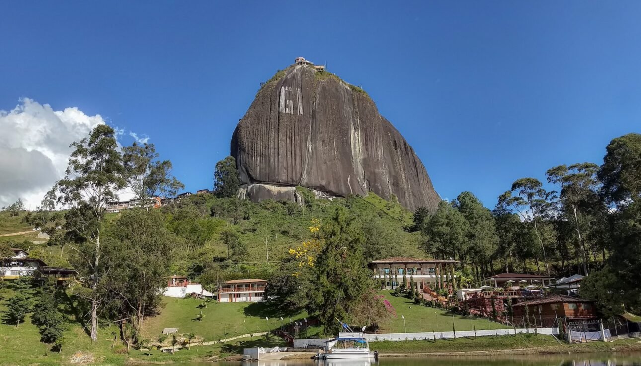 a large rock sitting on top of a lush green hillside