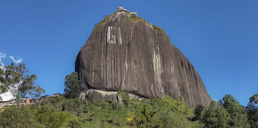 a large rock sitting on top of a lush green hillside