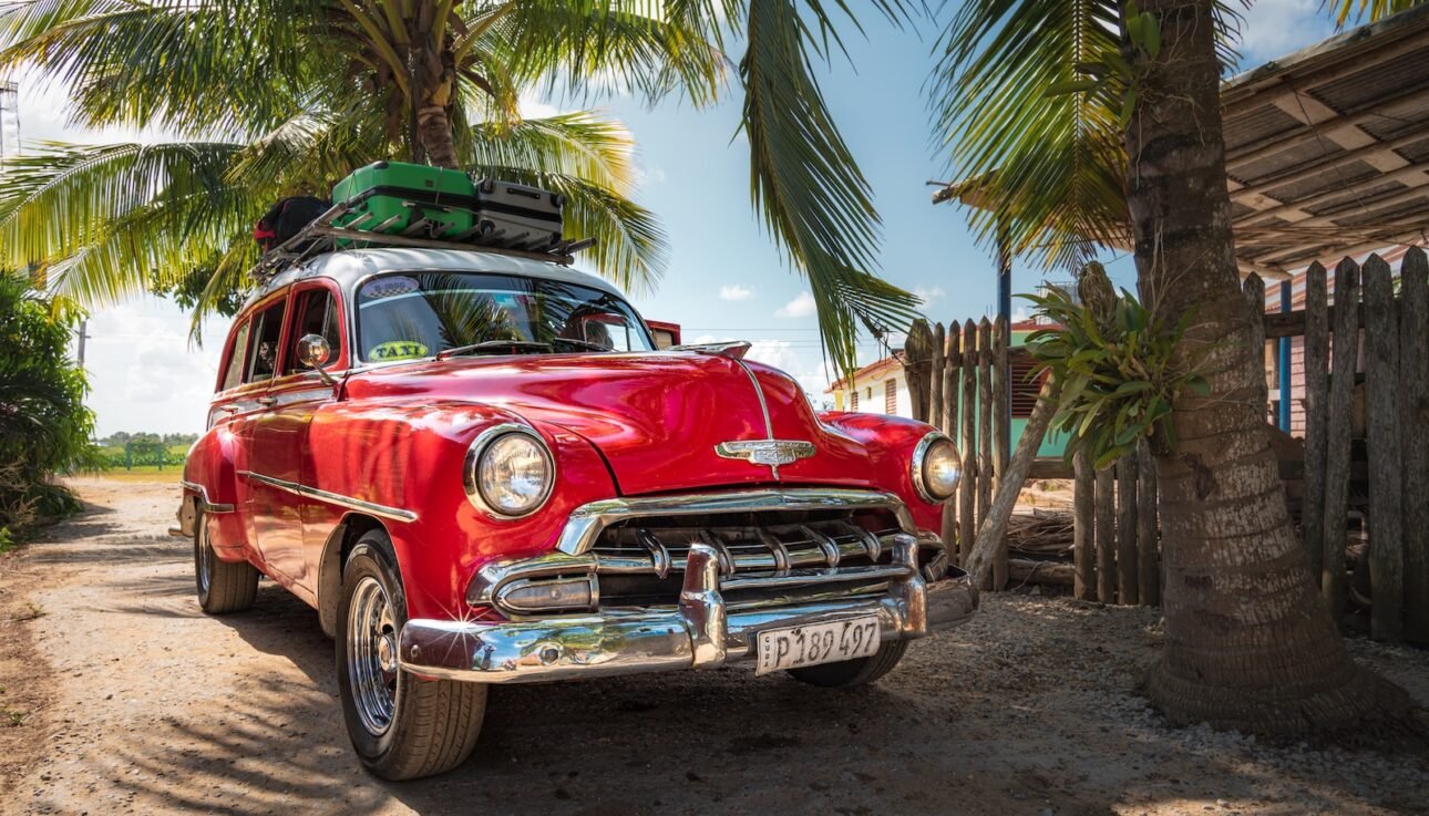 red and white vintage car parked beside palm tree during daytime