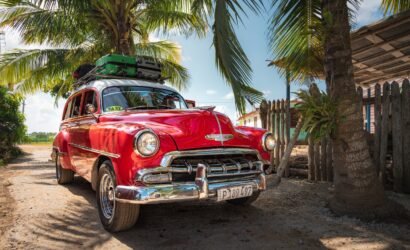 red and white vintage car parked beside palm tree during daytime
